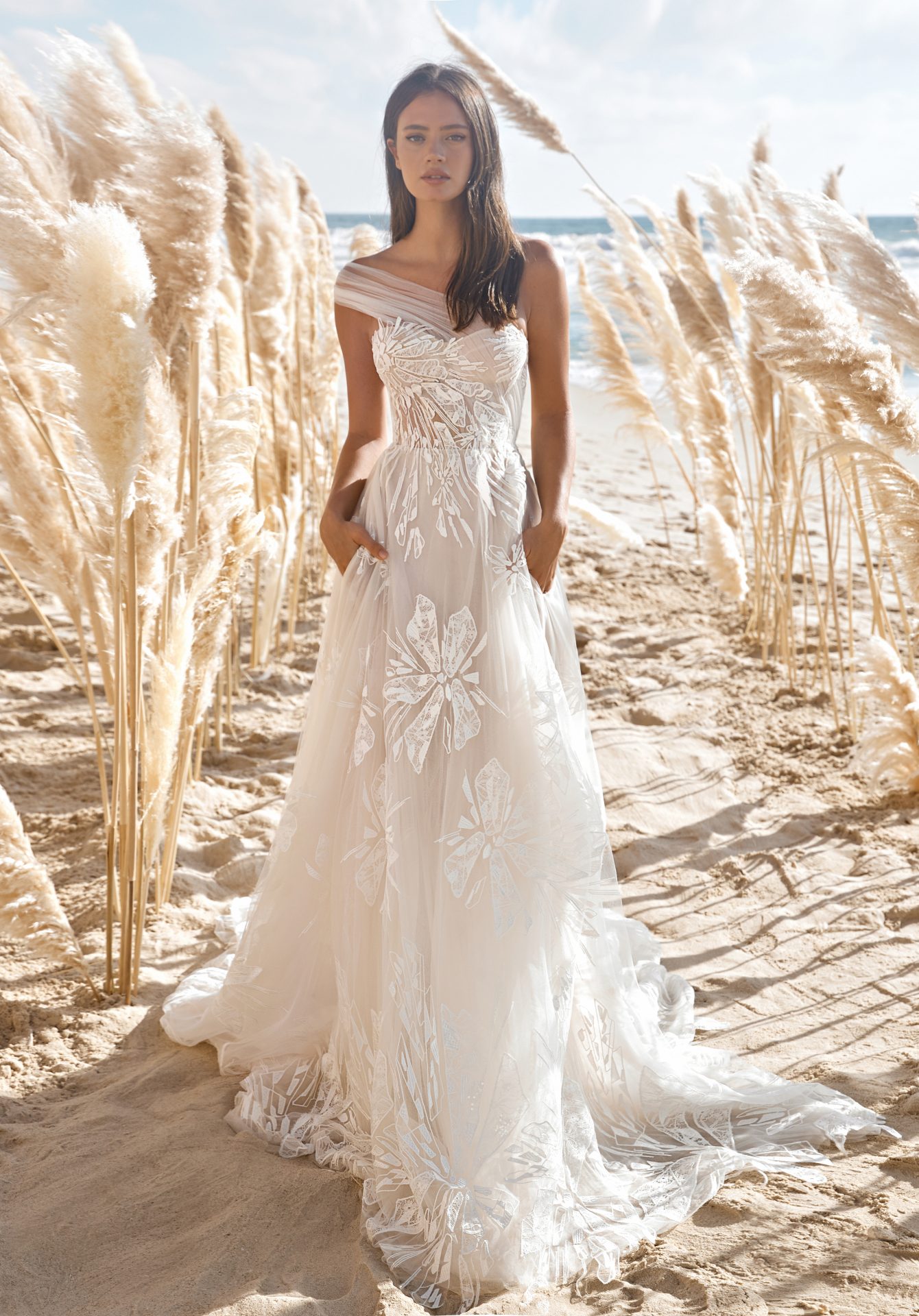bride on a beach wearing a tulle and lace one shoulder wedding dress by lee petra grebenau from dimitras bridal chicago